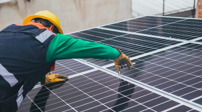 Profesional con casco revisa la colocación de paneles fotovoltaicos; imagen ilustrativa de obra no identificada