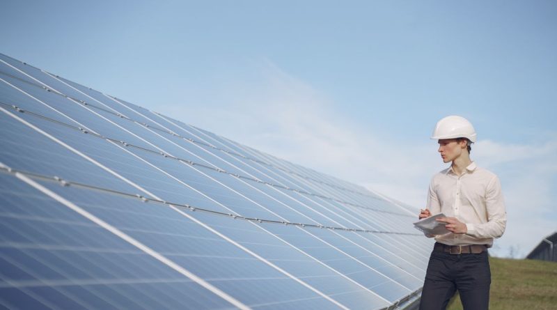 Persona con casco revisa paneles solares en instalación en suelo; imagen ilustrativa, no una cubierta catalana